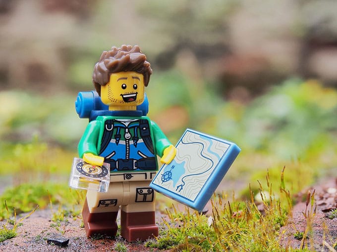 a cartoon figure holding a map and a compass trying to find the right location depicting how conversions can be increased with three simple questions.