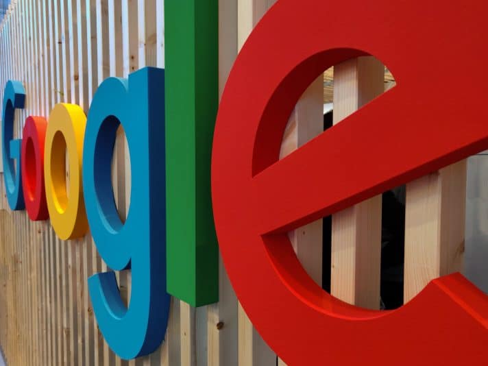 the picture of the Google letters on a wooden frame inside an office structure.