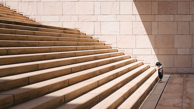 an image of a kid at the bottom of a set of steps depicting how growth and climbing the ranks is a process.