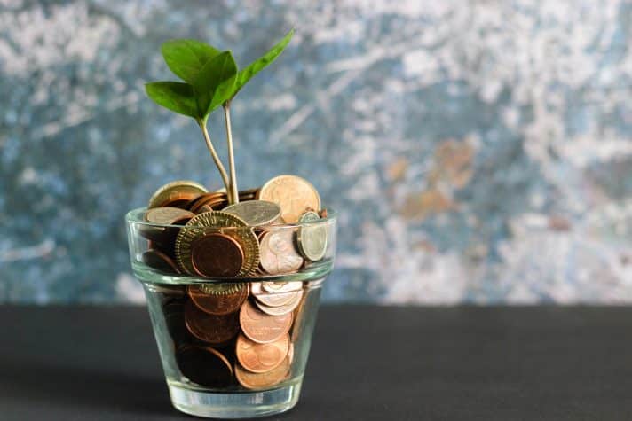 a cup filled with coins serving as the soil and a growing plant. This means growing business revenue.